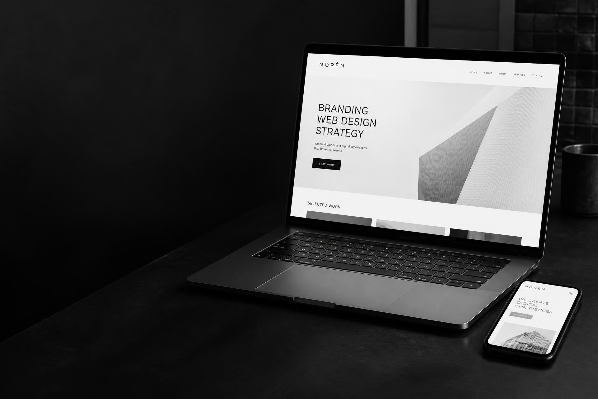 Notebook e smartphone sobre uma mesa elegante exibindo sites modernos criados pela DS Sites